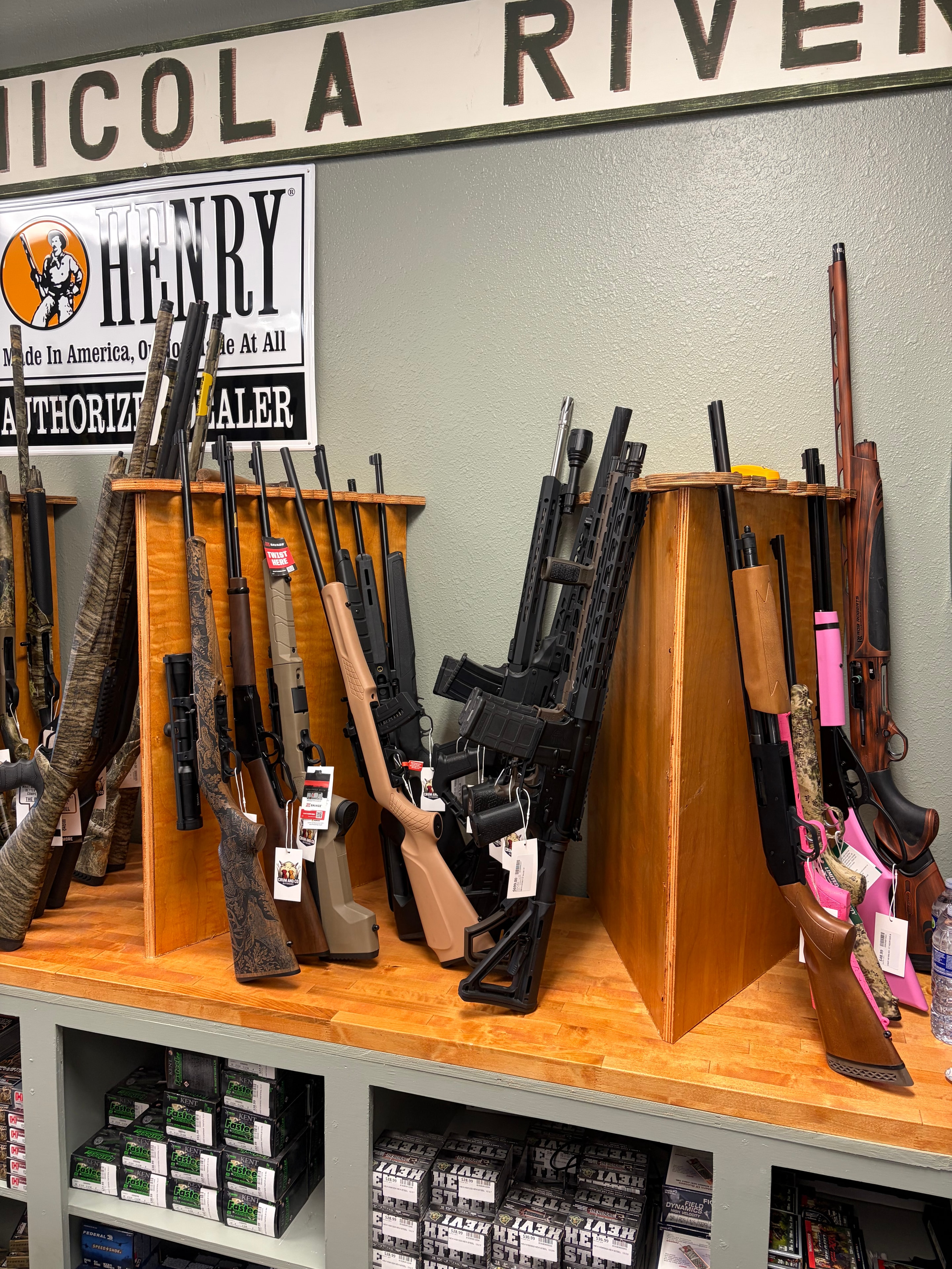 Shotguns, rifles and modern sporting rifles on wooden shelving at Crum and Co. Outdoors